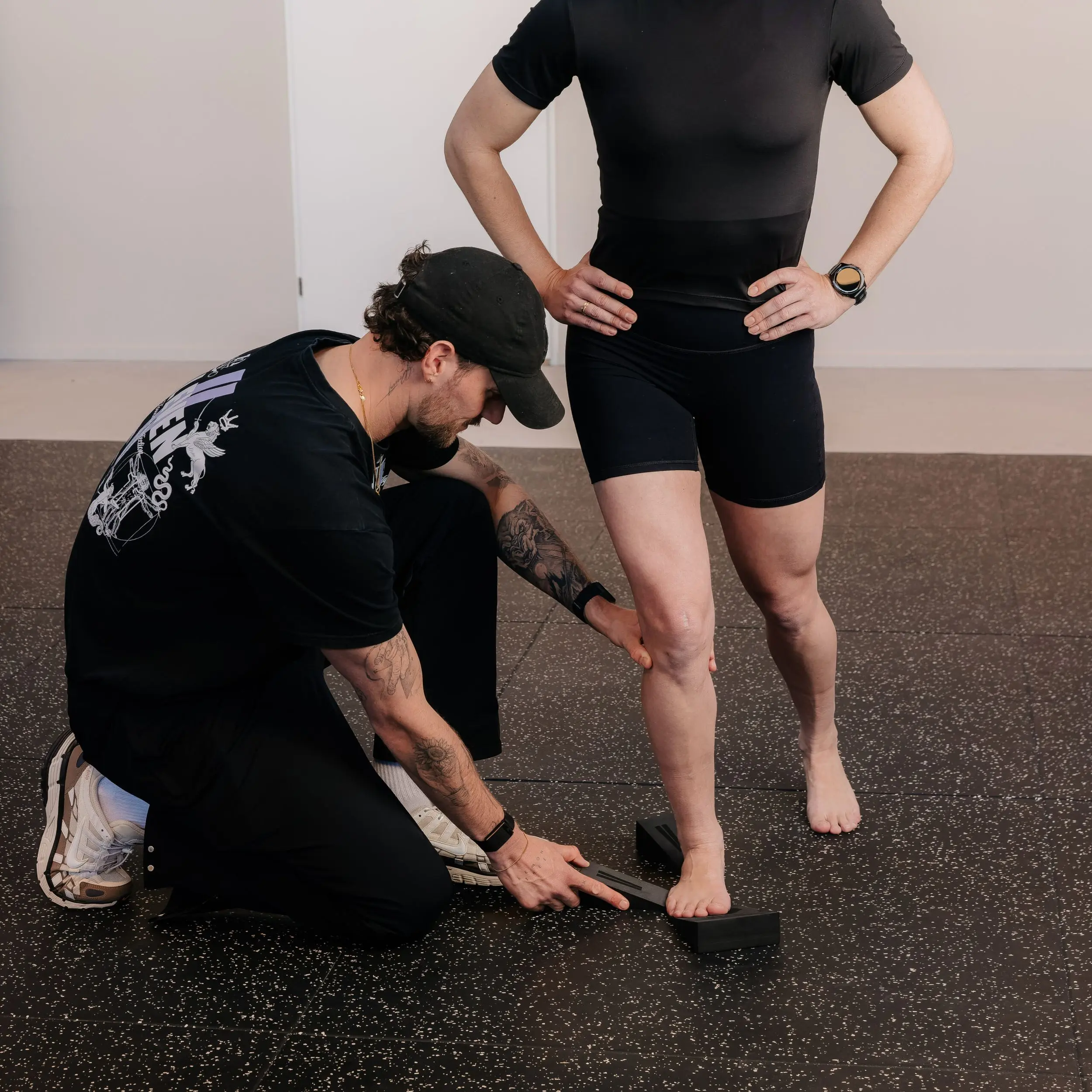Therapeut plaatst wedges onder de voeten van een sporter in de gym van ELEVEN