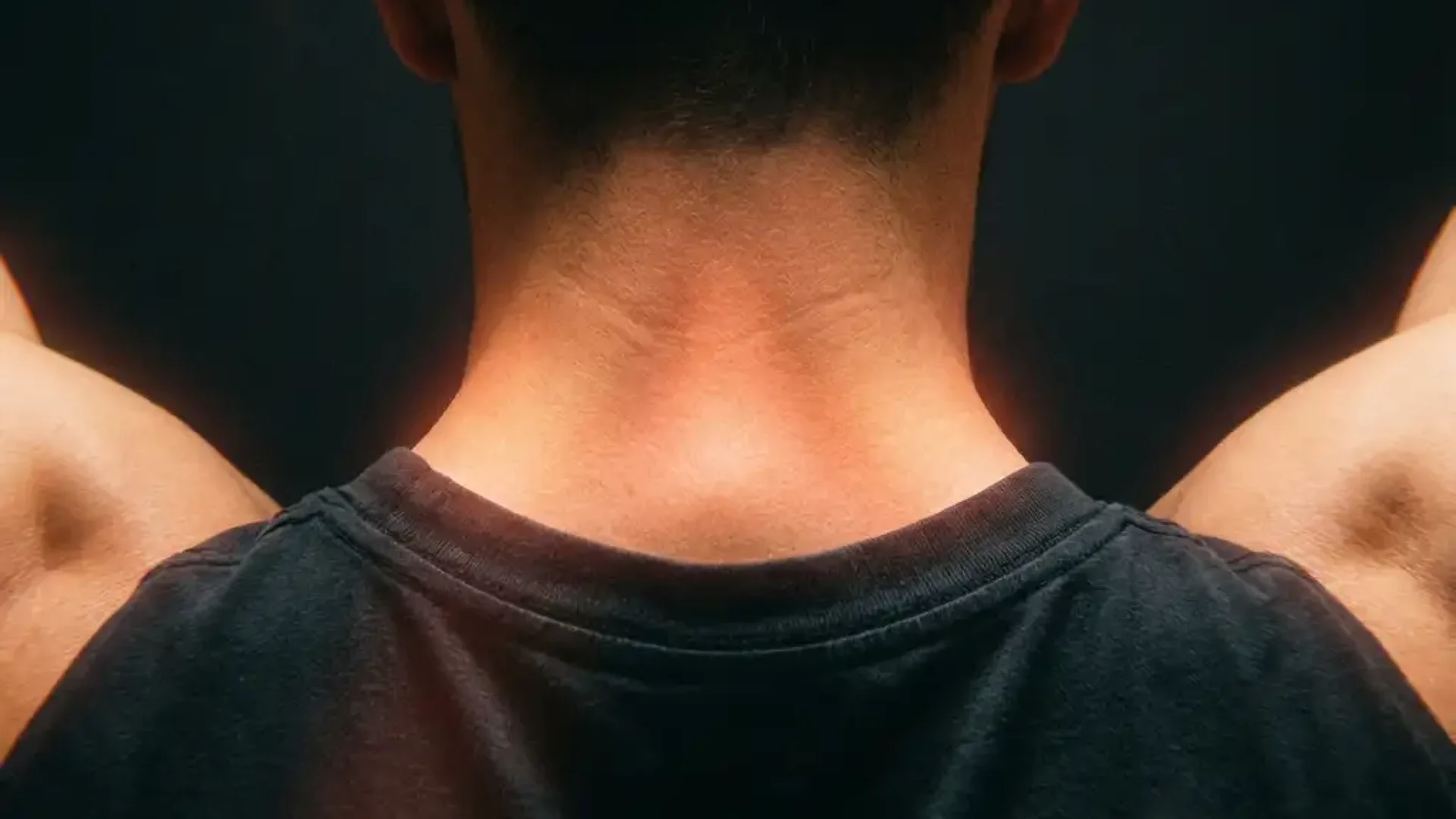 Mannelijke nek en schouders van achteren met rode gloed rond cervicale wervelkolom, dramatische belichting