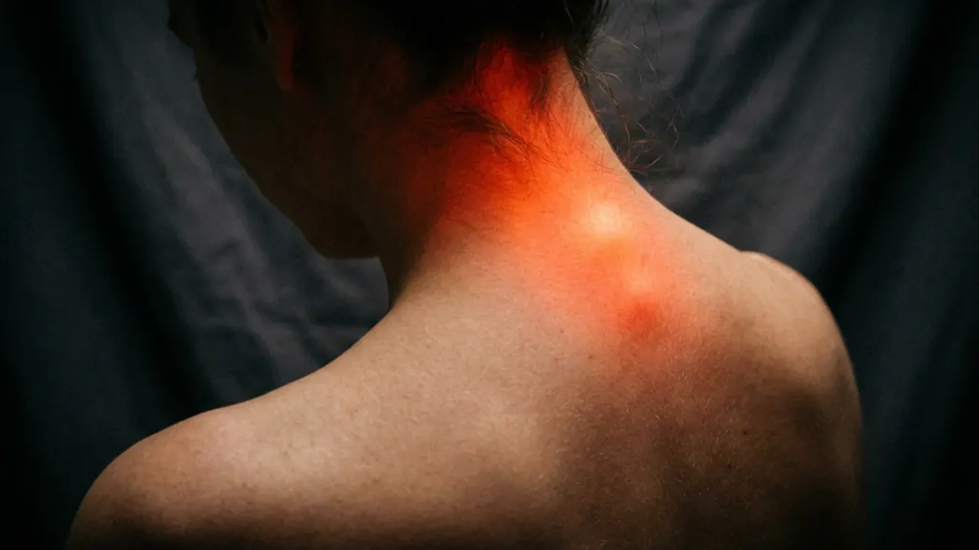 Nek en schouder met rode gloed die cervicale wervelkolom pijn en ontsteking visualiseert tegen donkere achtergrond