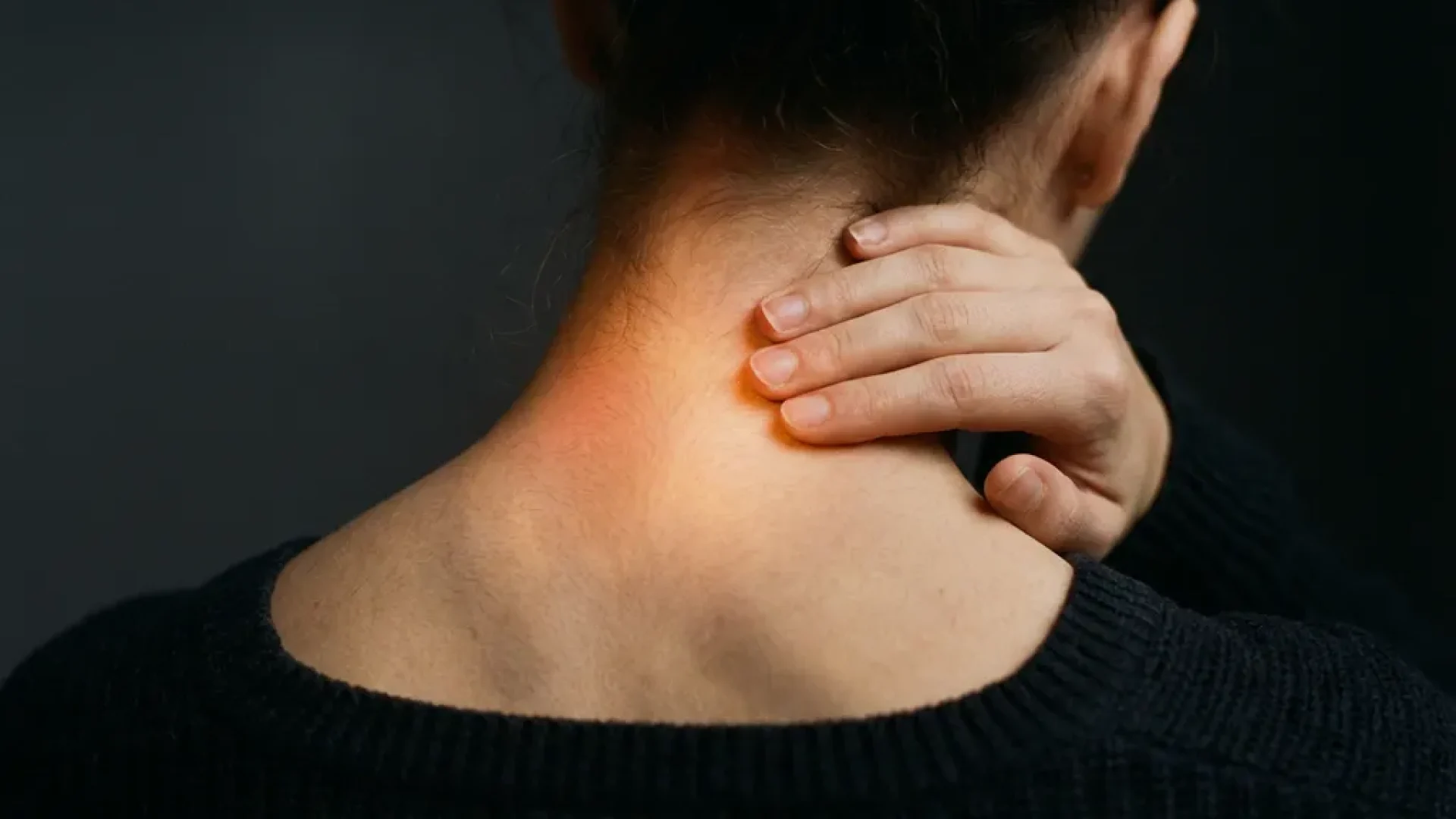 Persoon raakt nekspieren aan met warme roodoranje gloed die pijnverlichting en genezing symboliseert