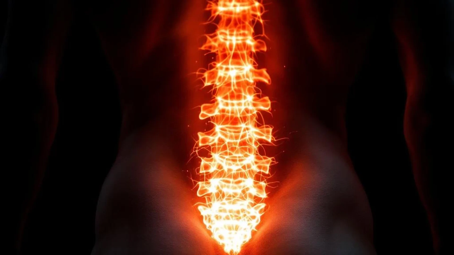 Menselijke onderrug met gloeiende oranje energie rond lumbale wervelkolom tegen zwarte achtergrond