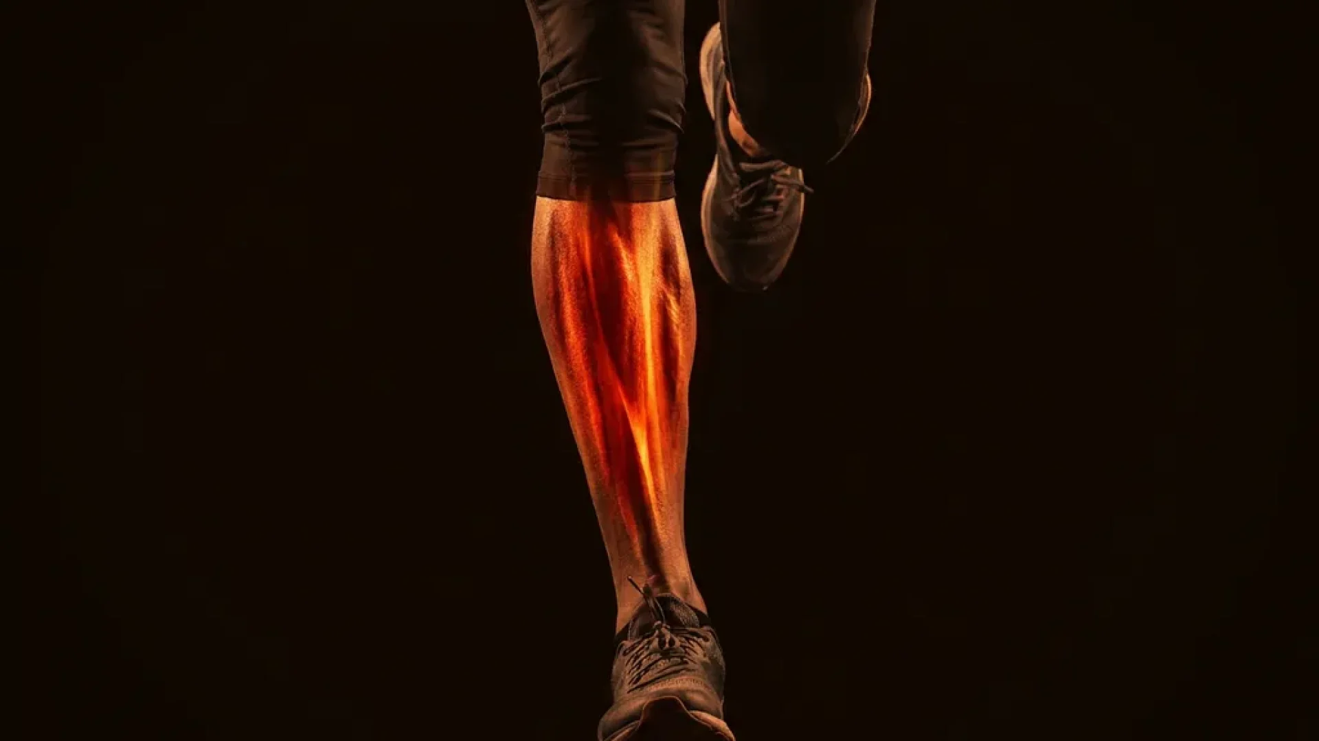 Gespierd onderbeen met gloeiend rood-oranje licht op het scheenbeen, wat pijn door shin splints visualiseert, tegen zwarte achtergrond.